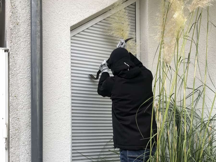 Einbrecher mit Brecheisen am Rollladen
